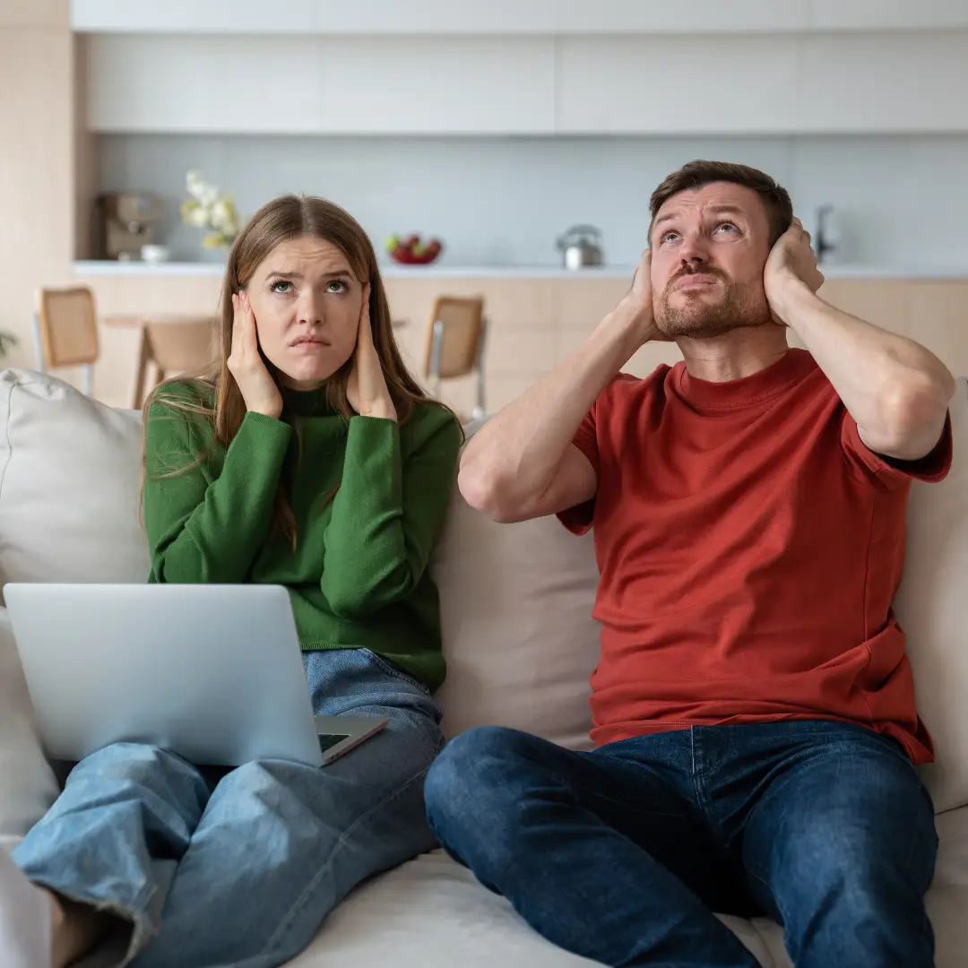 Stressed unhappy couple suffering from noisy neighbor. Disadvantages of living in apartment building